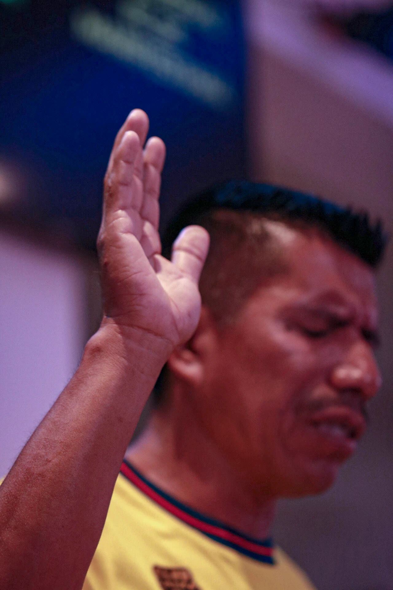 Asistente con los ojos cerrados y una mano levantada durante un momento de alabanza en Comunidad Más Alto