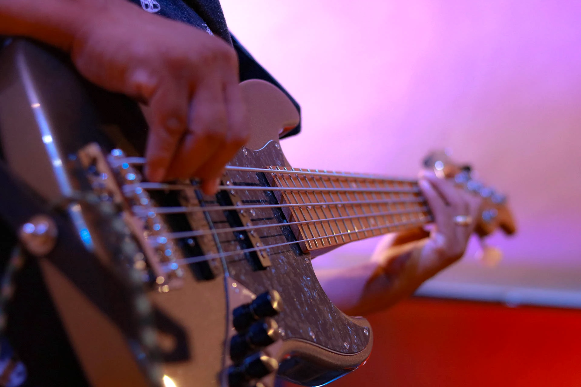 Primer plano de las manos de un músico tocando guitarra eléctrica en Comunidad Más Alto