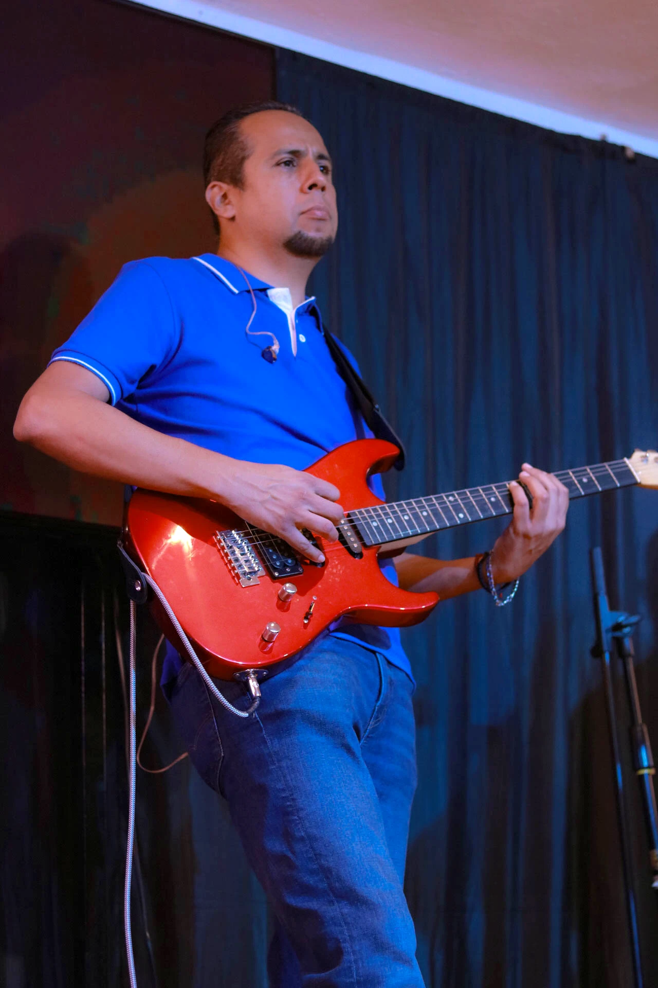 Guitarrista tocando una guitarra eléctrica roja en el escenario del Auditorio Comunidad Más Alto