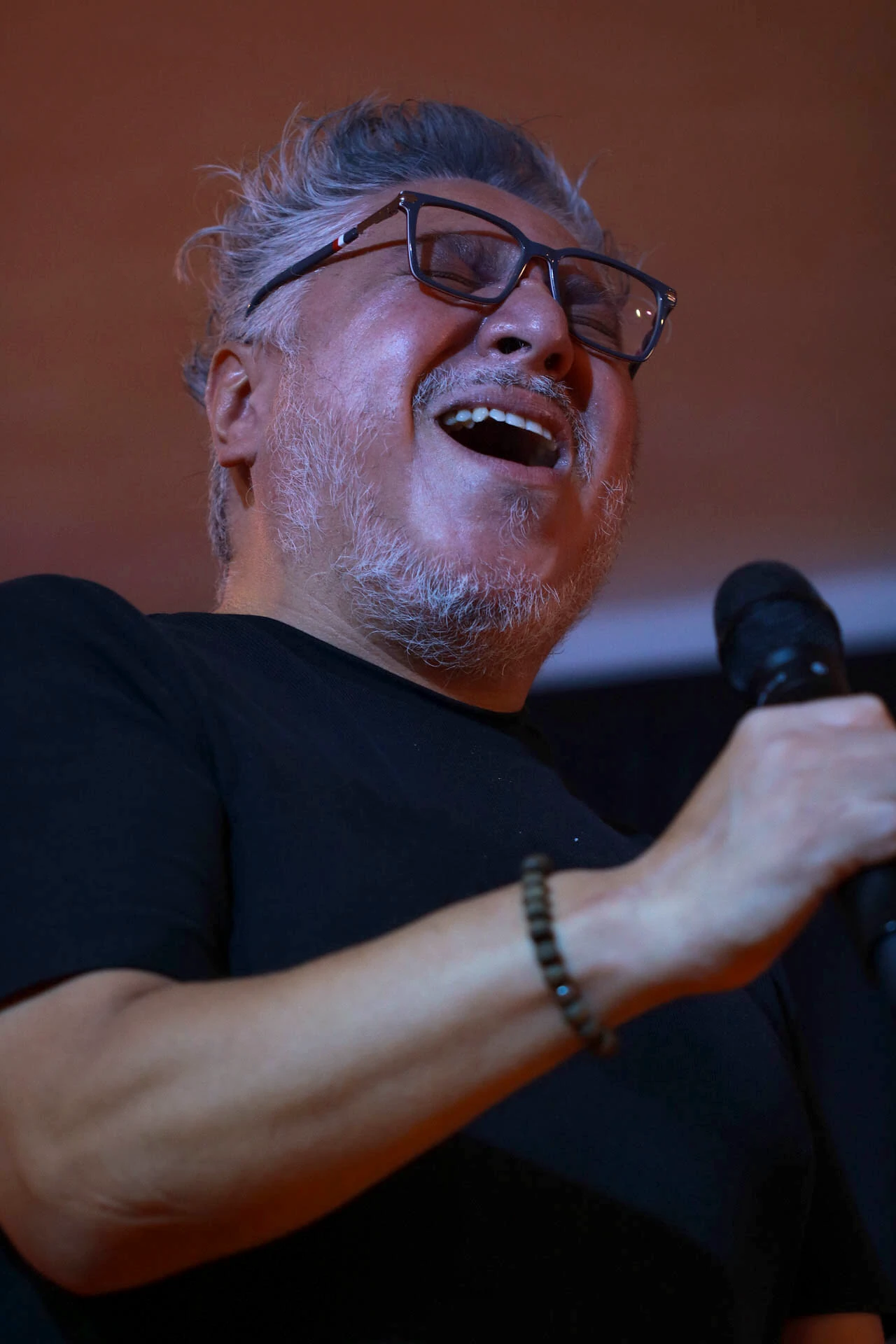 Orador sonriente con micrófono durante una presentación en Comunidad Más Alto