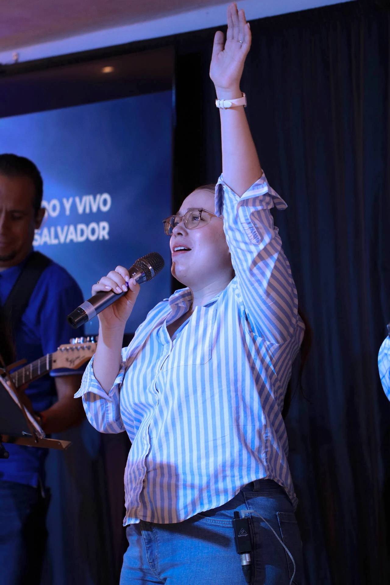 Vocalista con un brazo levantado durante una presentación de música en vivo en el Auditorio Comunidad Más Alto