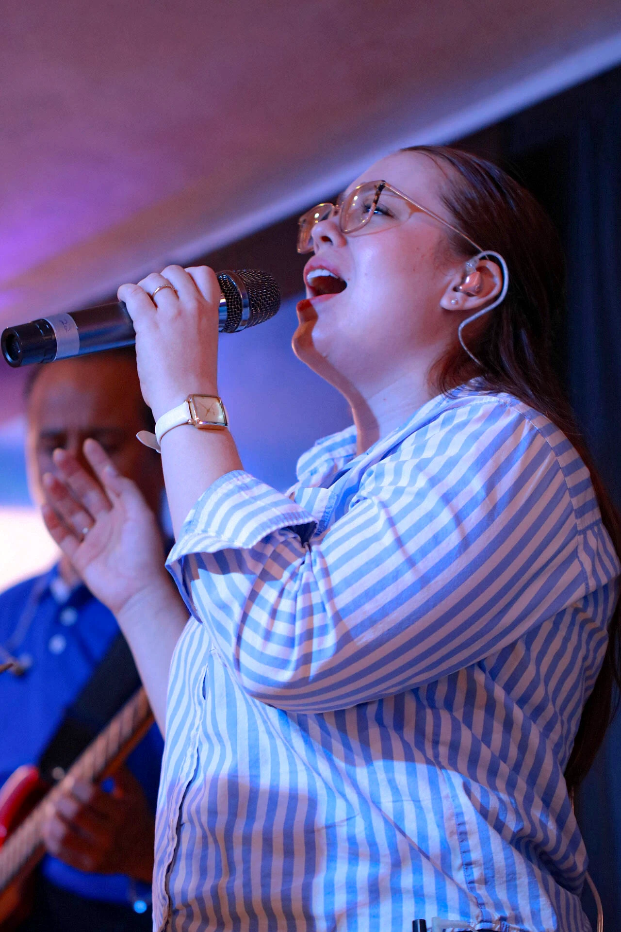 Retrato vertical de una vocalista cantando con micrófono en el Auditorio Comunidad Más Alto